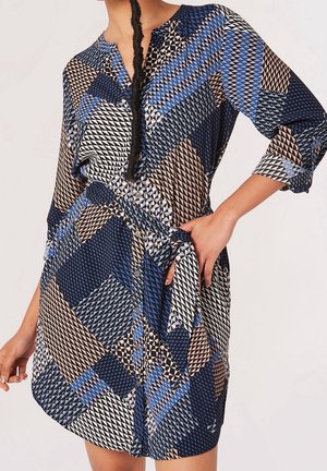 Modré a béžové šaty s geometrickými vzory, zapínání na knoflíky vpředu, tříčtvrteční rukávy a opasek vázaný v pase. Lehká látka.