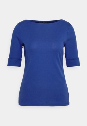 Haut bleu ajusté à manches courtes avec encolure bateau et poignets repliés sur fond blanc.