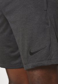 Pantalones cortos deportivos grises hechos de una tela suave, con una textura sutil, y un logo negro de Nike en el dobladillo inferior.