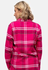 Camicia in flanella rosa con motivo a quadri e strisce bianche e grigie. Collo con bottoni e maniche lunghe. Tessuto morbido.