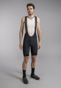 Black cycling bib shorts with a textured mesh upper. Features padded seat, fitted leg cuffs, and contrasting lighter top panel.