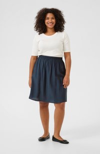 Navy blue, knee-length skirt with an elastic waistband, paired with a white fitted short-sleeve top and black flats. Smooth texture.