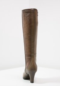Bota de cuero marrón hasta la rodilla con panel ribeteado texturizado, tacón afilado y detalles de costura, que presenta una superficie suave y un diseño elegante.