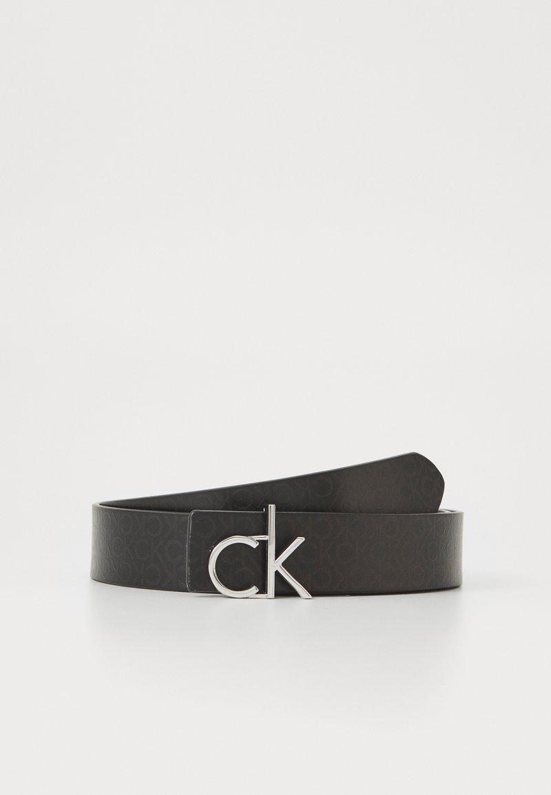 Černý kožený opasek s vyraženým vzorem loga, vybavený stříbrnou kovovou sponou s designem "CK". Hladký povrch, plochý design.