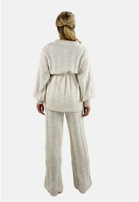 Crème-kleurig gebreid set bestaande uit een oversized pullover met ribbelsteken en bijpassende wijde broek met verticale strepen en een relaxte pasvorm.