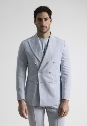 Chaqueta de traje de lino de doble botonadura en azul claro con solapas de muesca, dos bolsillos frontales y botones de color crema. Tejido texturizado con un acabado suave.