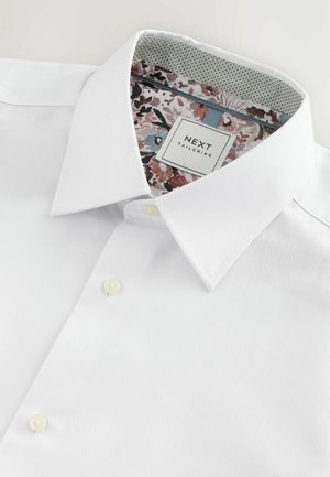 Vit skjorta med en strukturerad krage, texturerad tyg och blommönstrad innerkrage. Har klassisk knäppning.