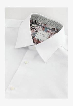 Valkoinen kauluspaita, jossa on jämäkkä kaulus, teksturoitu kangas ja kukkakuviollinen sisäkauluksen vuori. Klassinen nappisulku.