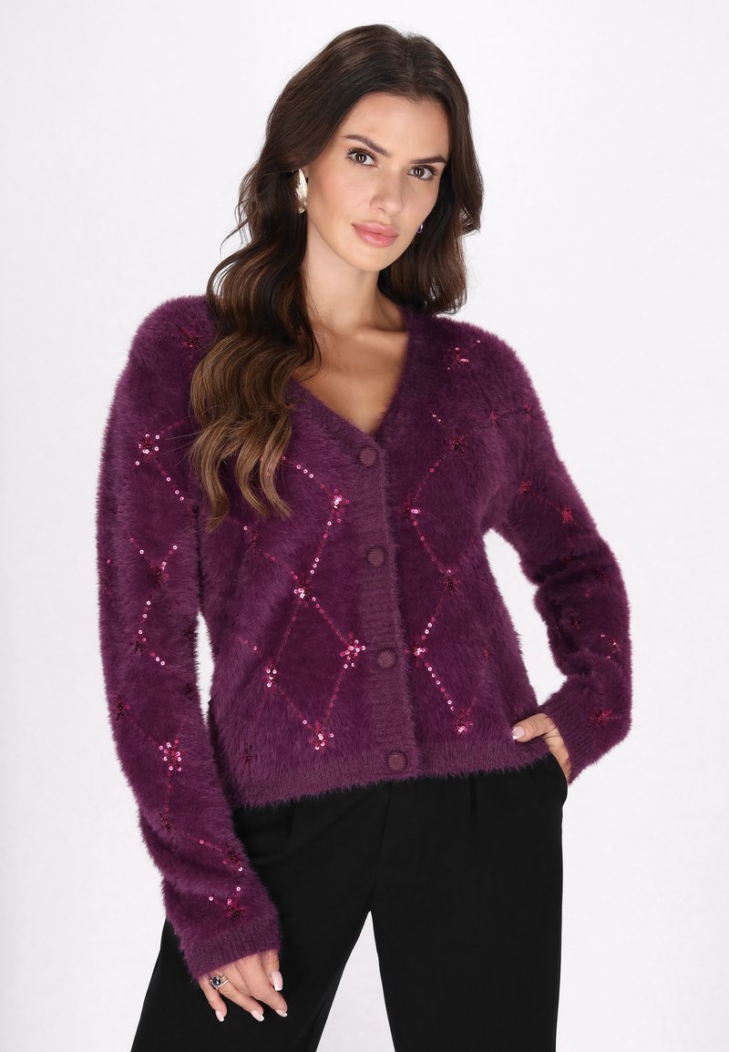 Cardigan morado y esponjoso con escote en V, patrón de lentejuelas en forma de diamante y cinco botones redondos, combinado con pantalones negros.