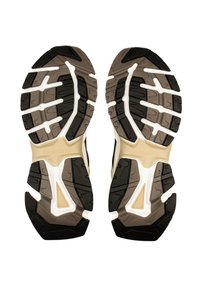 Sergio Tacchini träningsskor med en svart, beige och vit gummisula. Har djupa spår och strukturerad design för grepp och stabilitet.