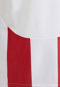 Tessuto bianco con texture liscia presenta audaci strisce verticali rosse. Il design include cuciture pulite e un aspetto di materiali misti.