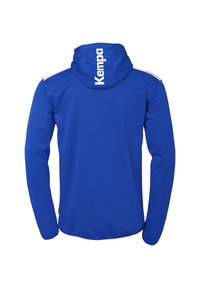 Blå atletisk jakke med hætte, der har en hvid accent på skuldrene og et stort "Kempa" logo på ryggen. Lavet af glat stof.