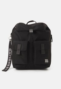 Zaino in tessuto nero con pattina pieghevole, due tasche frontali, una toppa con logo e una tracolla con motivo. Presenta un manico superiore e cerniere.