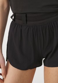 Pantaloni corti sportivi neri realizzati in materiale leggero. Presentano un cinturino elastico con accenti in rete e fessure laterali per una maggiore mobilità.