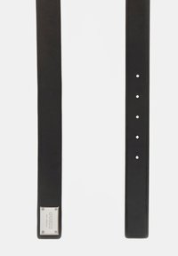 Juodas odinis diržas su sidabriniu metaliniu ženkleliu, kuriame pasirinktas prekės ženklas. Diržas turi kelis reguliavimo skylutes ant lygios, vientisos konstrukcijos.