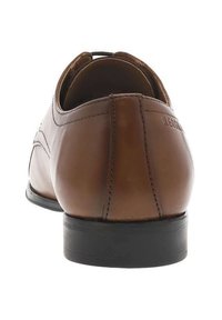 Scarpa da uomo in pelle marrone con texture liscia, punta arrotondata e suola in gomma nera. Presenta dettagli di cucitura e logo del marchio sul tallone.