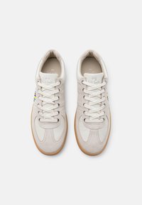 Pair of white leather sneakers with gum soles, white laces, and colorful striped detail on the sides, viewed from above on a plain background.