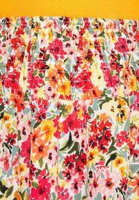 Tissu floral avec un design plissé présentant des fleurs rouge vif, orange et jaune sur un fond clair, complété par une ceinture côtelée jaune.