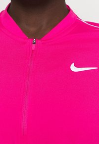 Pink Nike athletic top with a high collar, zip closure, and white logo accent. Smooth fabric and fitted design for active wear.
