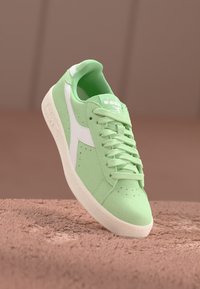 Sneaker verde in suede con dettagli bianchi, punta arrotondata, design con lacci e dettagli perforati sui lati. Suola in gomma.