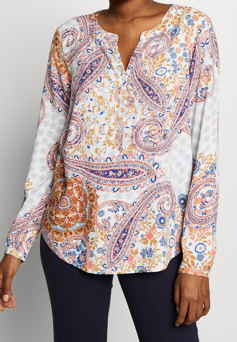 Blouse à manches longues boutonnée en blanc avec un motif cachemire multicolore. Comprend des accents bleus, orange et floraux ; tissu léger.