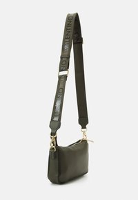 Zelená kožená crossbody taška s obdélníkovým tvarem, texturovaným povrchem a nastavitelním popruhem, který má potisk s logem a zlaté kovové detaily.