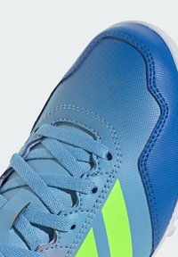 Blue athletic shoe featuring a textured upper, neon green accents, a smooth toe cap, and standard lacing system.