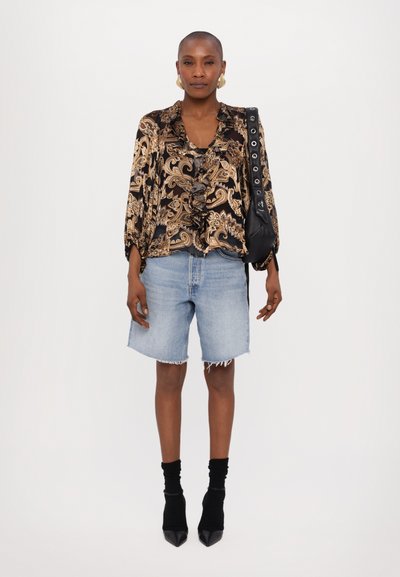 Black and gold paisley blouse with ruffled neckline, light blue denim cut-off shorts, black ankle socks, and pointed-toe heeled shoes.