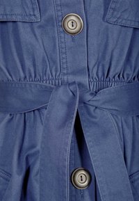 Niebieska bawełniana sukienka z wcięciem w talii, z zapięciem na guziki i związanym paskiem. Gładka tekstura z dwoma przednimi kieszeniami.