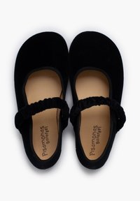 Mocasines de terciopelo negro al estilo Mary Jane con correas elásticas y plantillas color tostado etiquetadas como "Pisamonas Barefoot" sobre un fondo blanco.