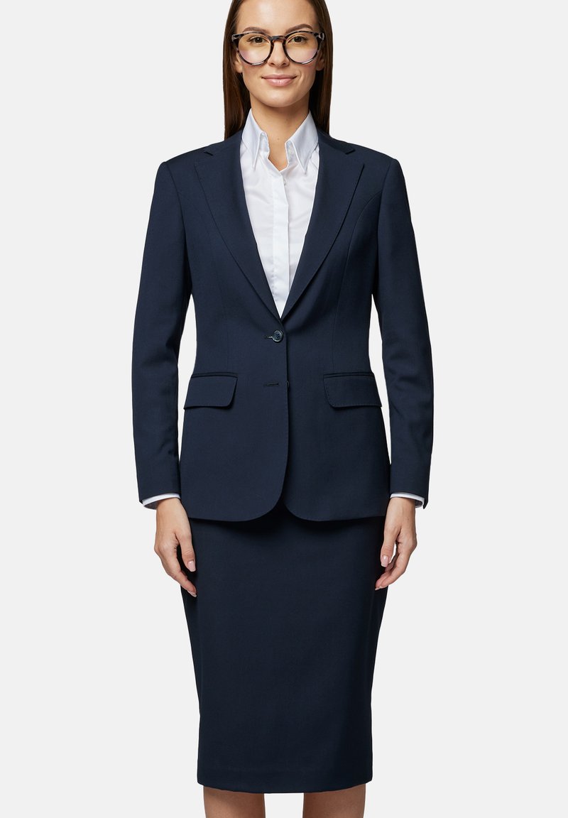 Granatowy damski garnitur składający się z dopasowanej marynarki z dwoma kieszeniami i ołówkowej spódnicy, obie wykonane z gładkiej, dopasowanej tkaniny.