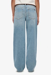 Jasnoniebieskie, szerokie dżinsy o wykończeniu spranym. Posiadają dwie tylne kieszenie oraz zamek błyskawiczny. Teksturowany materiał denim z widocznym przeszyciem.