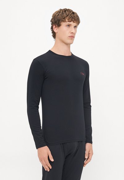 T-shirt noir à manches longues en matériau lisse et extensible. Présente un col rond et un petit logo brodé de manière subtile sur la poitrine.