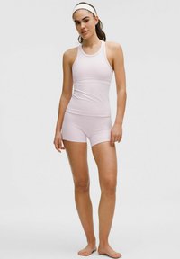 Pale pink athletic tank top and shorts set, made of stretchy fabric. Features a racerback design and a fitted silhouette. No patterns or accents.
