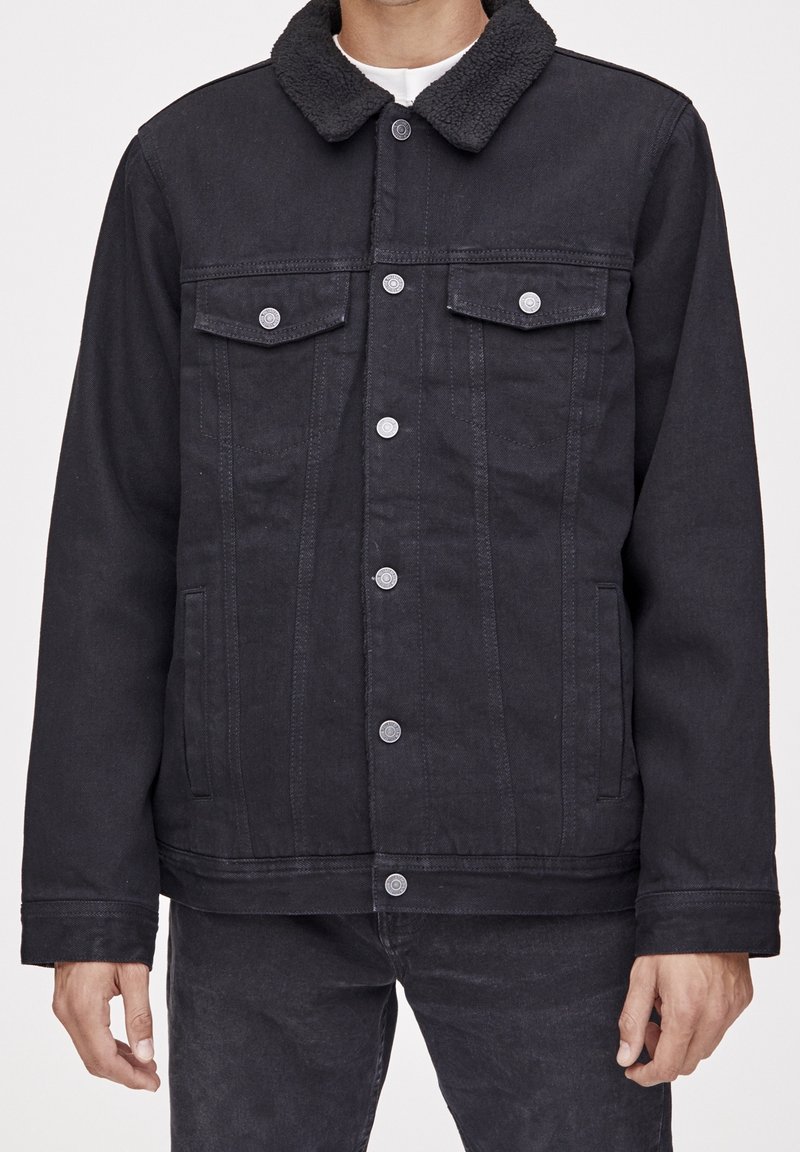 Veste en denim noire avec un col duveteux, deux poches poitrine et une fermeture à boutons sur le devant. Caractérisée par une coupe décontractée et des détails de couture subtils.