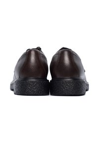 Brązowe skórzane buty z fakturowaną powierzchnią, o niskim profilu, zaokrąglonym czubku i czarnych gumowych podeszwach. Minimalistyczny design, bez widocznych logo.