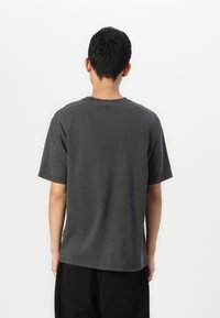 Short-sleeve gray cotton t-shirt with a crew neckline, featuring a relaxed fit and minimal stitching details. Back view shown.