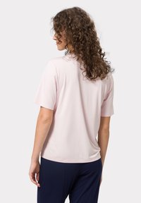 Camiseta de manga corta color rosa claro con un corte relajado, textura suave y cuello redondo, combinada con pantalones azul marino.