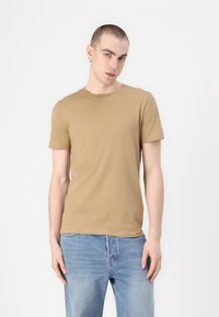 Ταν κοντομάν�ικο μπλουζάκι από μαλακό βαμβακερό ύφασμα, με κλασικό σχέδιο λαιμόκοψης και απαλή υφή. Φορεμένο με ανοιχτό μπλε τζιν.