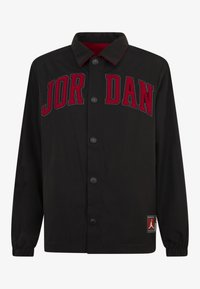Svart jakke med dristig rød "JORDAN" brodering, trykknapper og en teksturert innerfôr. Inkluderer en logopatch ved nederkanten.