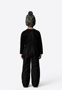Black snow suit with adjustable straps and elastic waist, paired with a black and grey zebra-patterned knit beanie with a pom-pom on top.