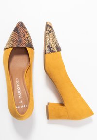 Scarpe con tacco alto in suede giallo, con punta affusolata e un accento in stampa pitone marrone testurizzato sulla parte anteriore. Design con tacco a blocco.