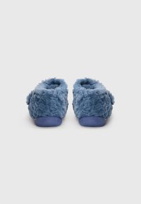 Pantuflas azules y esponjosas con un exterior texturizado y suelas de goma azul sólidas. Parte trasera redondeada y diseño abierto para un uso fácil y rápido.