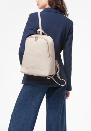 Zaino in pelle beige con forma arrotondata, doppie cerniere e finitura testurizzata. Spallaccio singolo imbottito e maniglia superiore aggiuntiva.