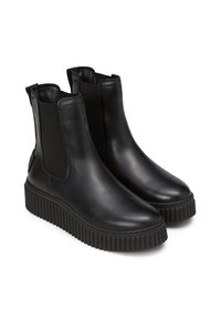 Bottines en cuir noir avec des panneaux élastiques sur les côtés, bout arrondi et semelle en caoutchouc noir texturé avec des nervures verticales.