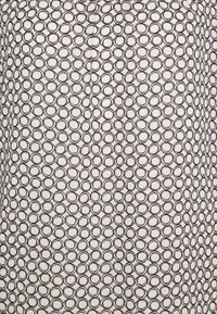 Tissu noir et blanc présentant un motif répétitif de cercles entrelacés. Le matériau semble lisse avec une légère texture.