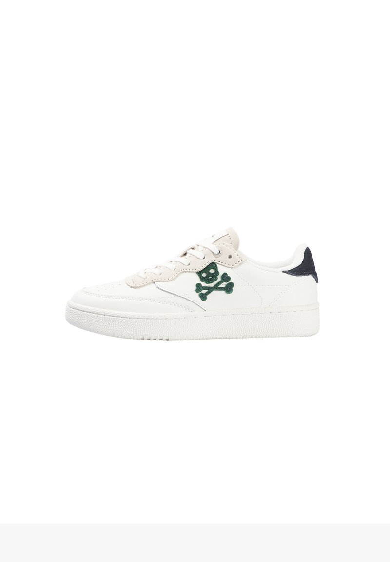 Zapatilla baja blanca con acentos en beige, logo de calavera y huesos cruzados verdes en el lateral y pestaña del talón negra.