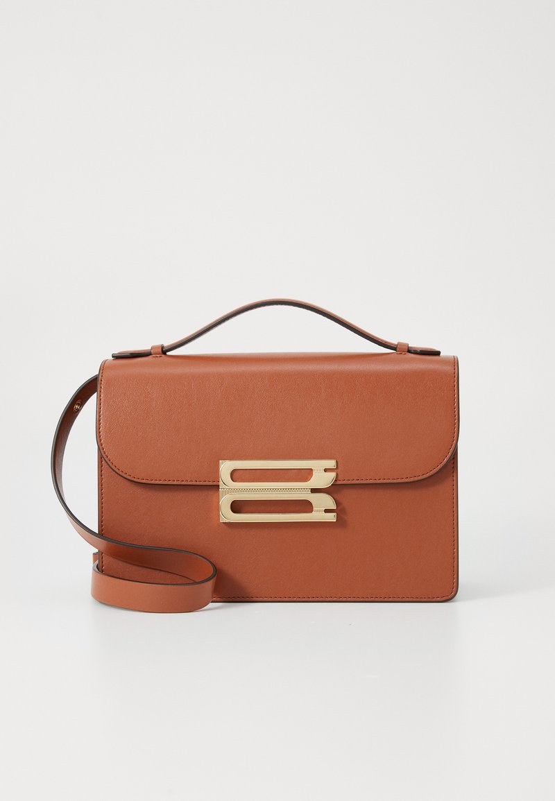 Brązowa skórzana torebka o zdefiniowanym kształcie, z zamknięciem w kolorze złotym i regulowanym paskiem na ramię. Gładka tekstura i klapa na górze.