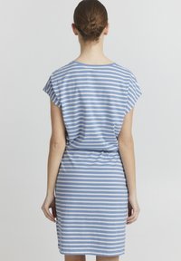 Kék és fehér csíkos ruha, rövid ujjakkal, kerek dekoltázzsal, megkötött derékkal, térd hosszúságú, puha anyagból készült, laza szabású.