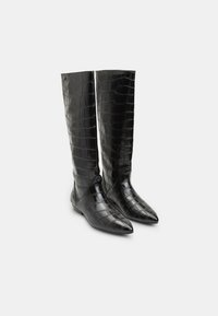 Bottes noires jusqu'aux genoux avec une texture brillante en cuir de crocodile, à bout pointu et finition lisse. Comprend un minimum de garniture.